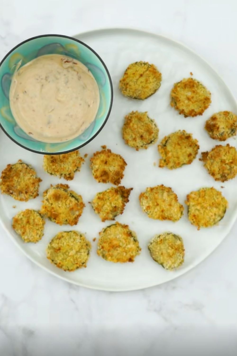 Baked fried pickles arranged on a plate with dipping sauce, proving weight watchers recipes can still include salty, crunchy snacks.