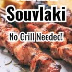 Close-up image of juicy chicken souvlaki skewers on a white platter with fries and lemon in the background, overlaid with the text “Greek Chicken Souvlaki — No Grill Needed.”