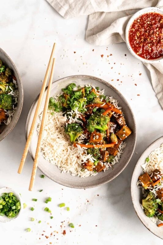 A vibrant stir-fry with crispy tofu, fresh vegetables, and a sweet ginger sauce over rice.