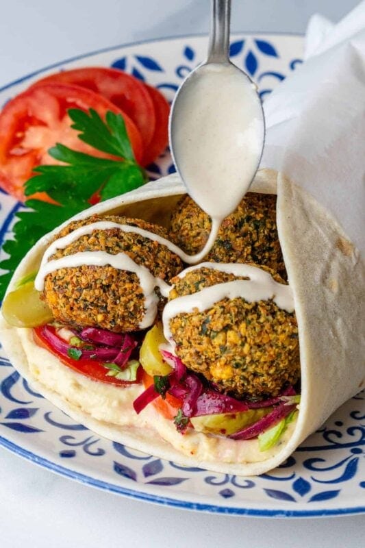 Crispy falafel wrapped in a soft pita with fresh veggies and creamy sauce for a delicious handheld meal. 