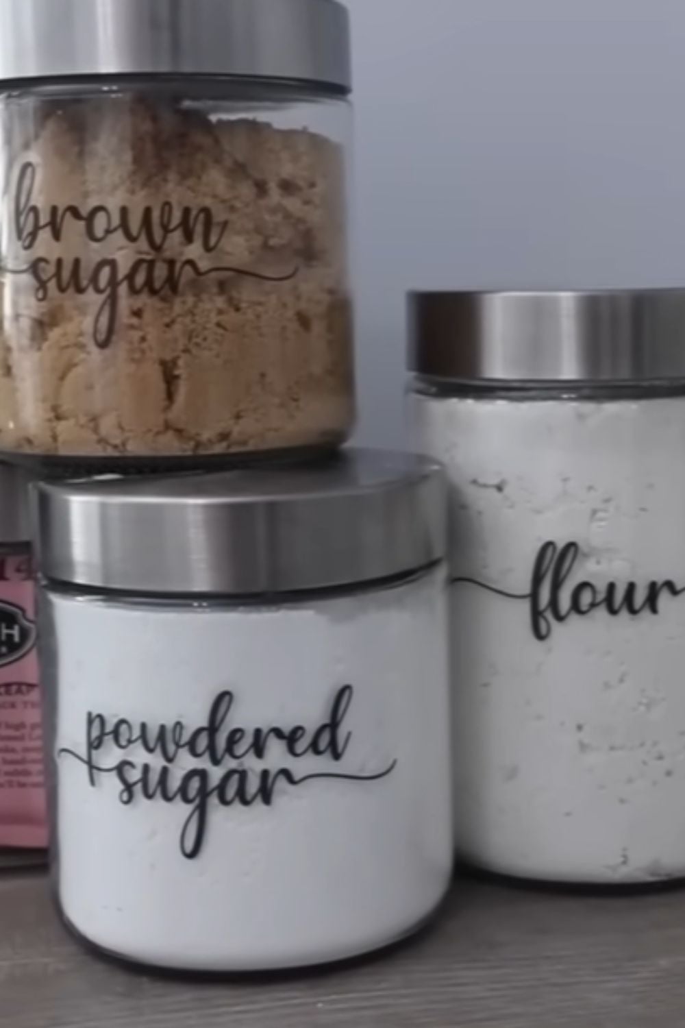 Clear pantry jars labeled for sugar and flour showing one of my favorite dollar store hacks for making pantry shelves look clean, organized, and easy to use every day.