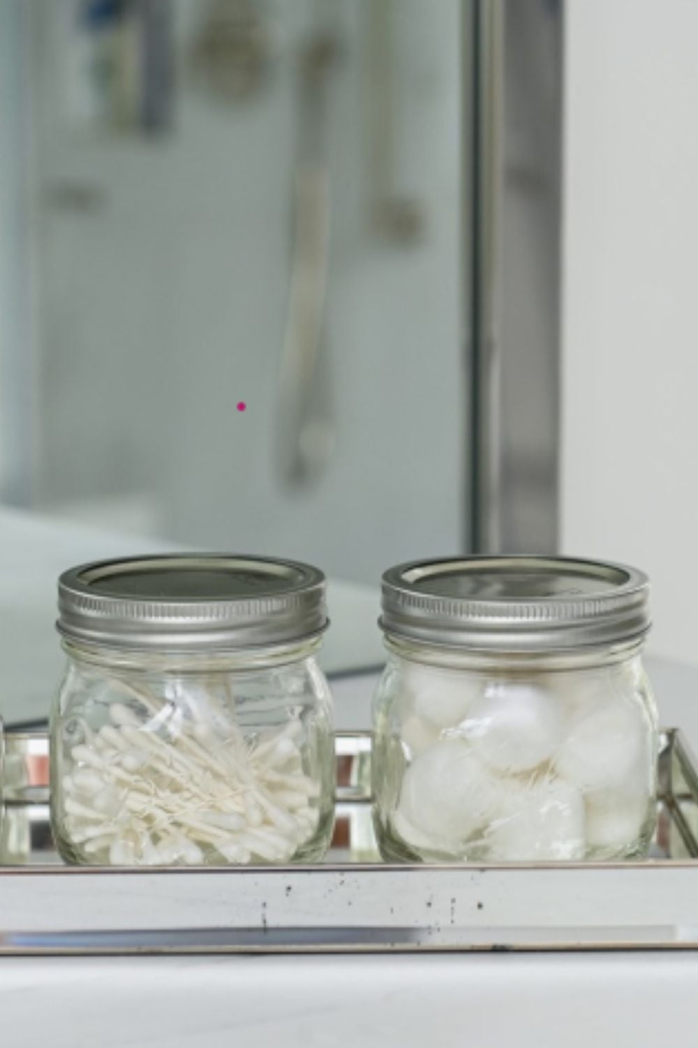 Small jars storing cotton balls and Q-tips, a classic dollar store hack that keeps bathroom counters neat and easy to maintain.