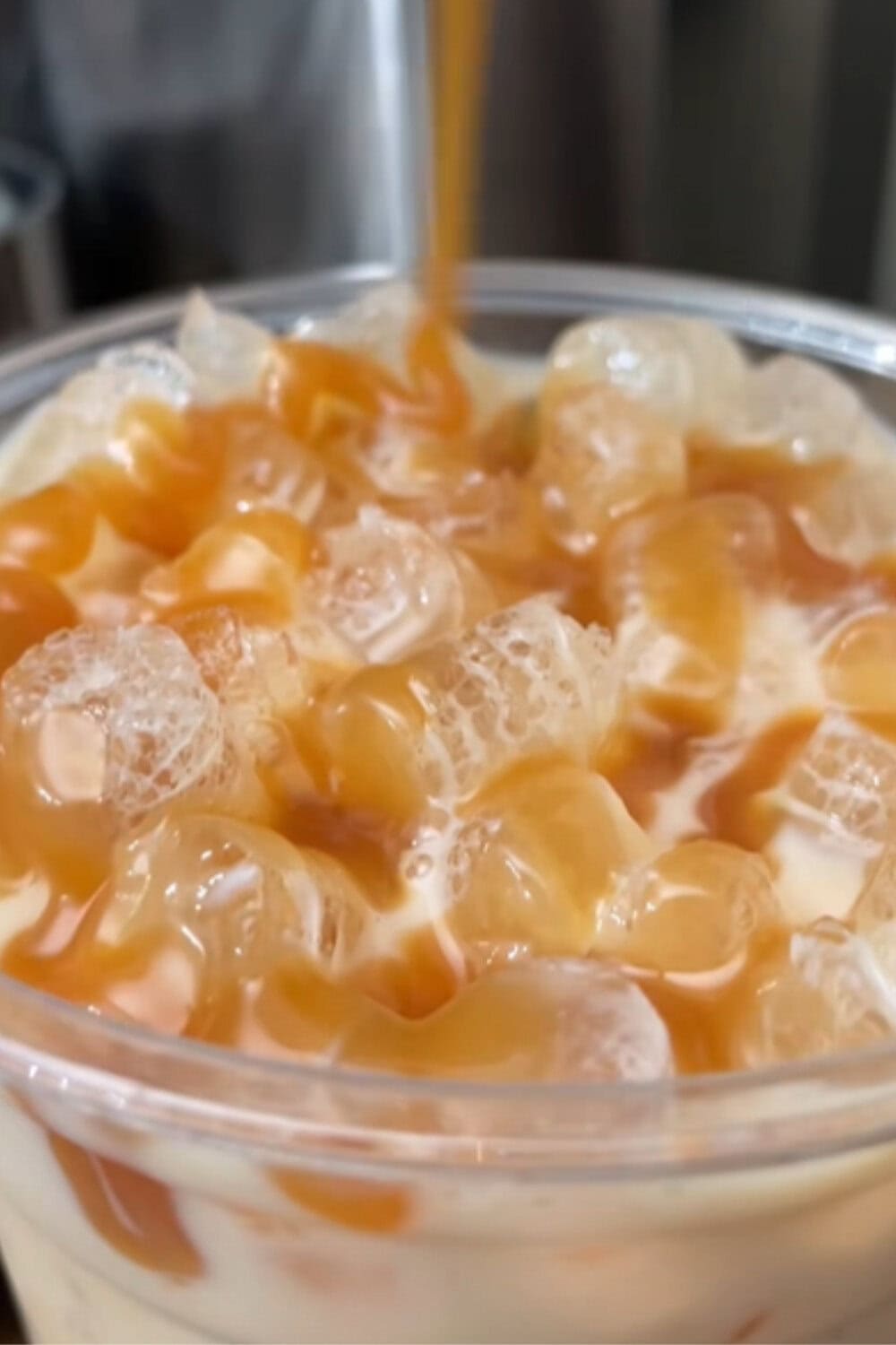 Iced coffee recipe with crushed ice covered in sweet caramel drizzle and creamy white chocolate swirls, captured close-up for a rich, glossy look.