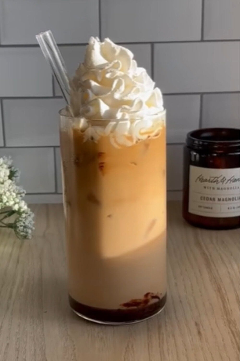 Iced coffee recipe topped with a tall swirl of whipped cream, chocolate drizzle at the bottom, and a festive peppermint mocha flavor.